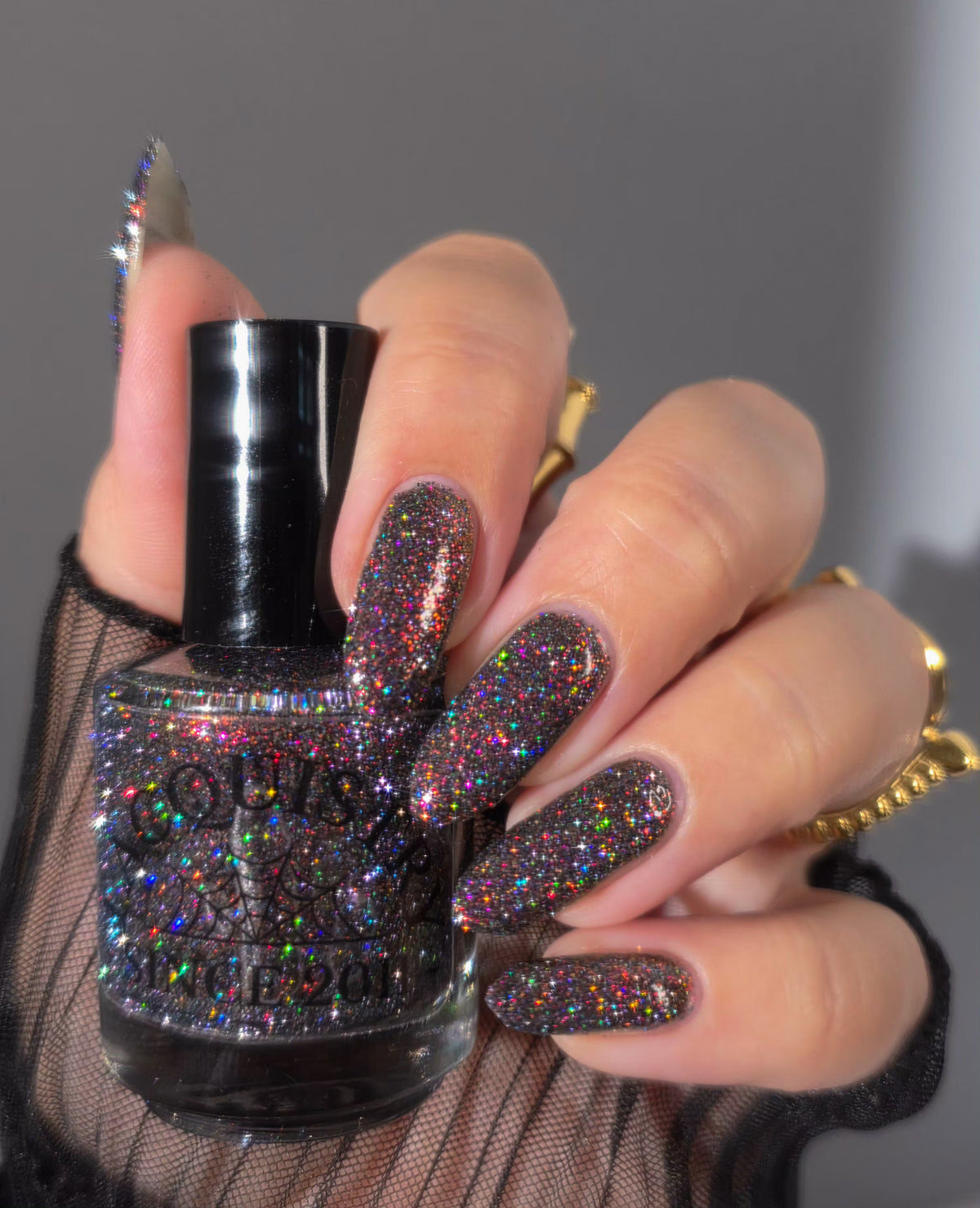 red sparkles with lavender reflective glitter in a dark base over nails holding bottle that says LACQUISTRY SINCE 2011
