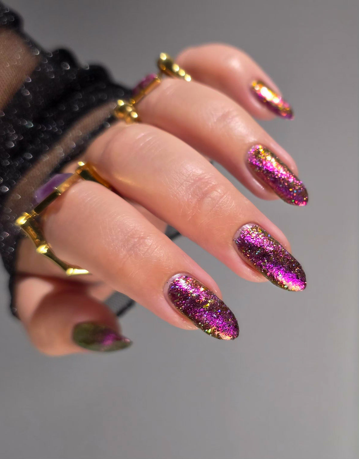 flakie magnetic polish showing red, orange, gold, green flakes, holo glitter, and magnetic effect of fuchsia to purple