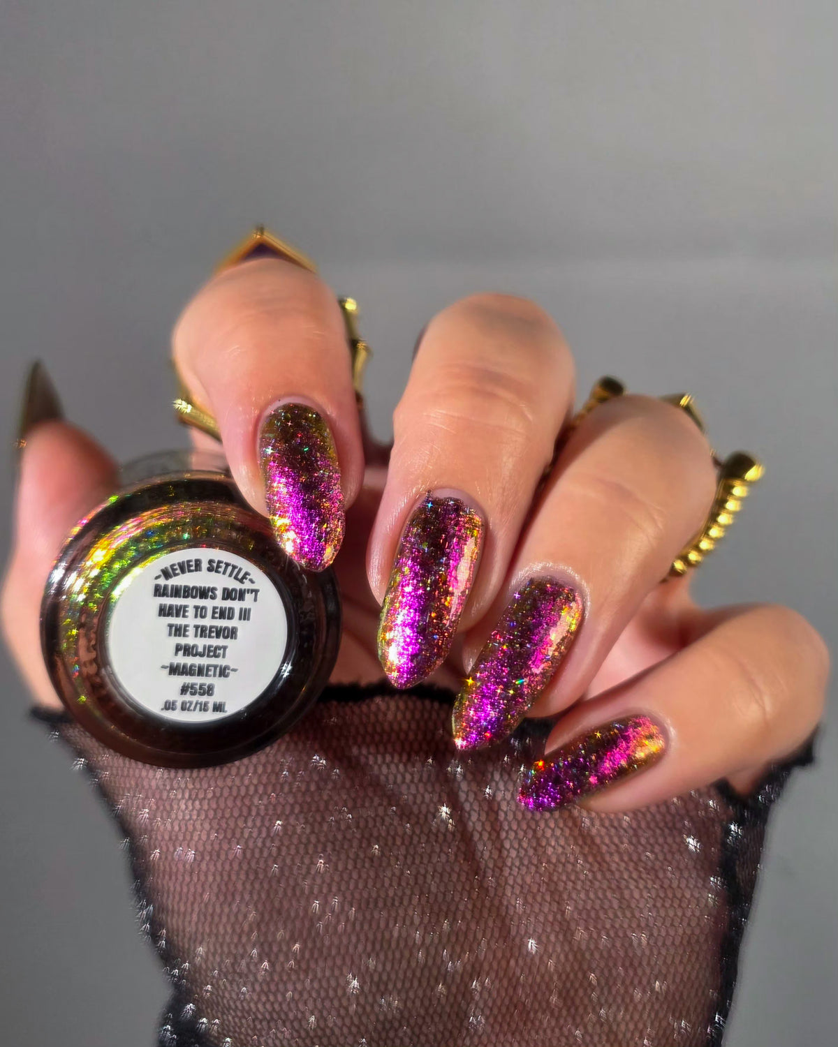 flakie magnetic polish showing red, orange, gold, green flakes, holo glitter, and magnetic effect of fuchsia to purple showing bottom label that says rainbows don't have to end III the Trevor Project