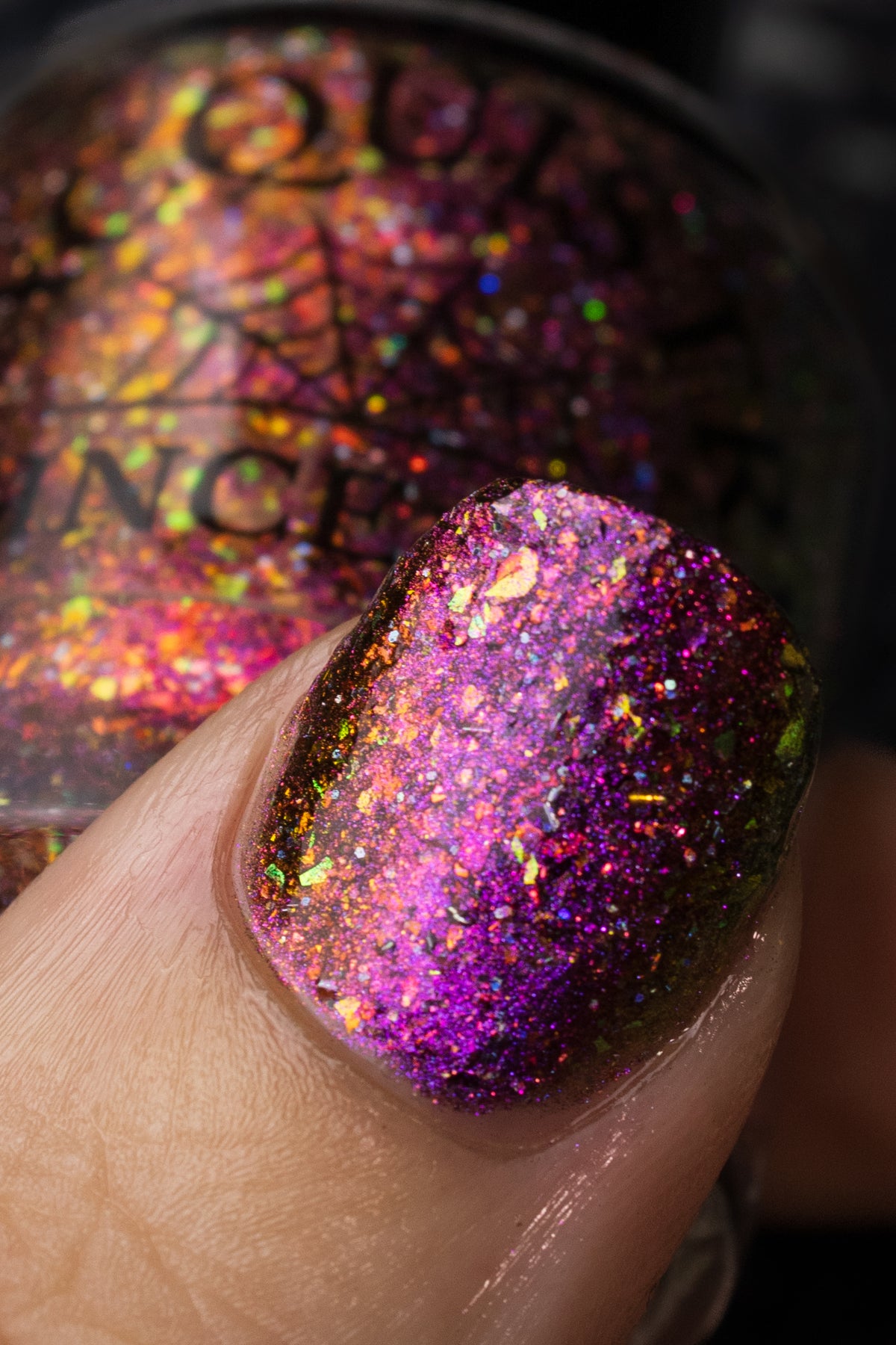 flakie magnetic polish showing red, orange, gold, green flakes, holo glitter, and magnetic effect of fuchsia to purple