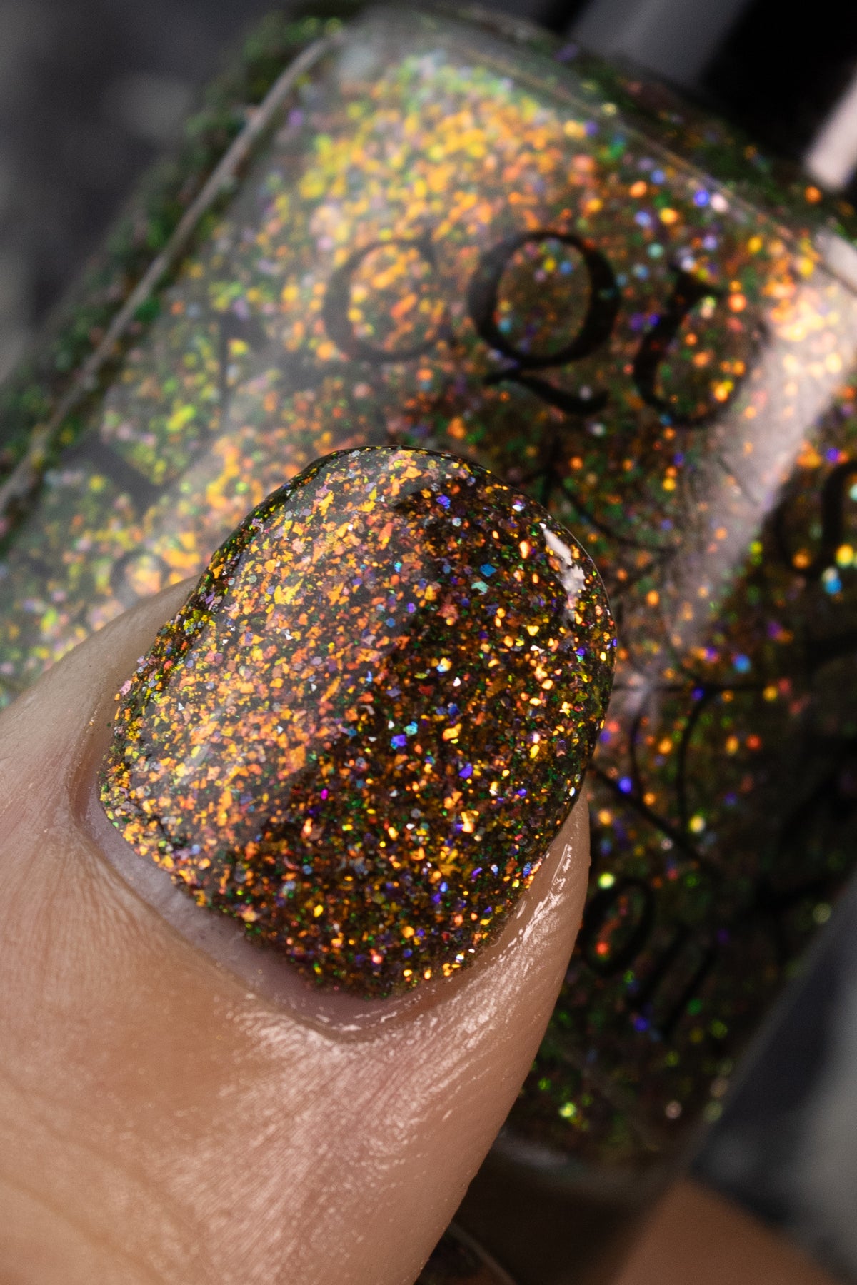 nails painted with sparkly glittery polish showing pink, red, orange, gold, lavender holo glitters in a darkened base color