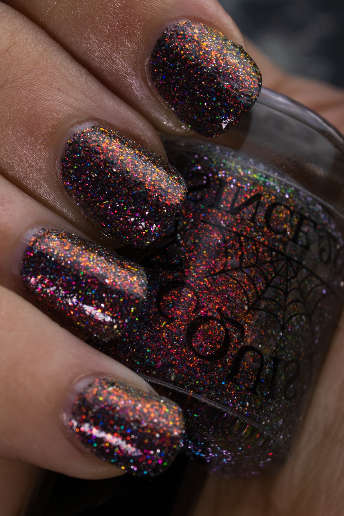 red sparkles with lavender reflective glitter in a dark base over nails holding bottle that says LACQUISTRY SINCE 2011
