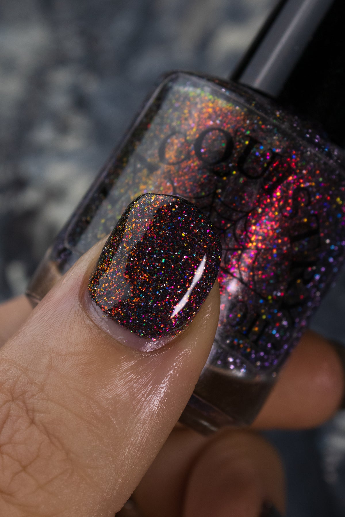 red sparkles with lavender reflective glitter in a dark base over nails holding bottle that says LACQUISTRY