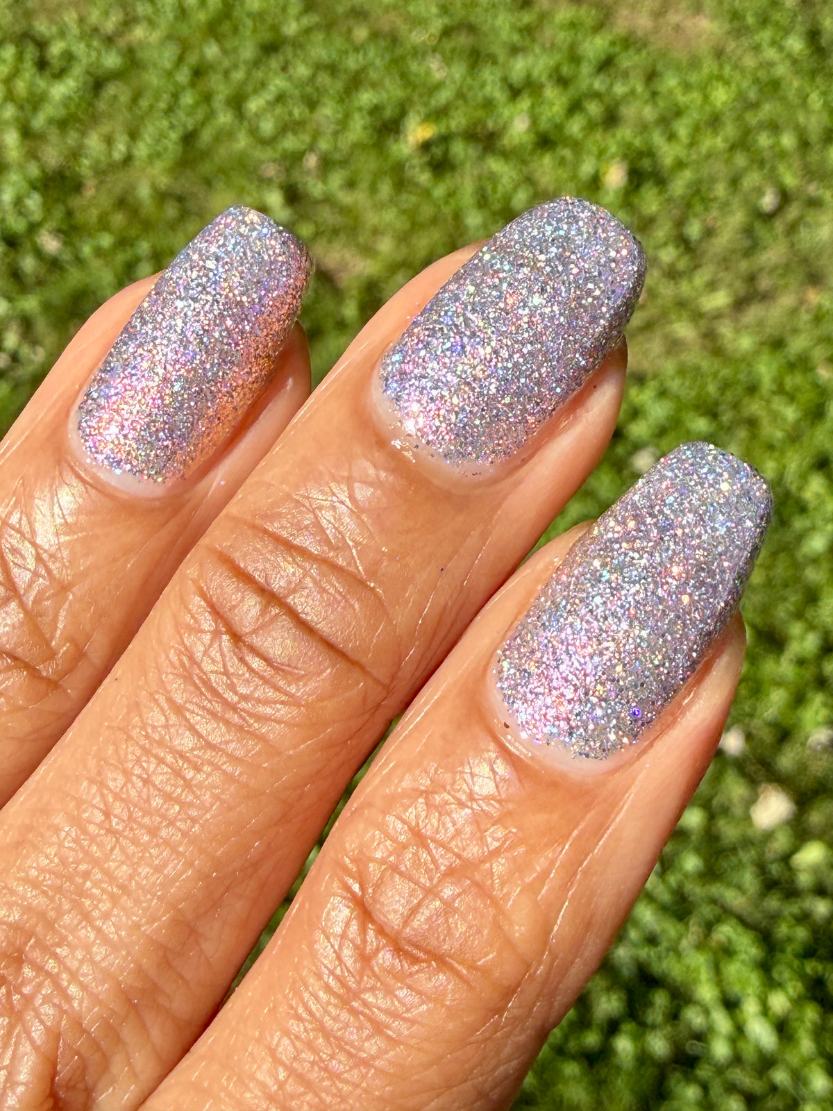 lavender sparkle and holo glitter pink nail polish with grass background