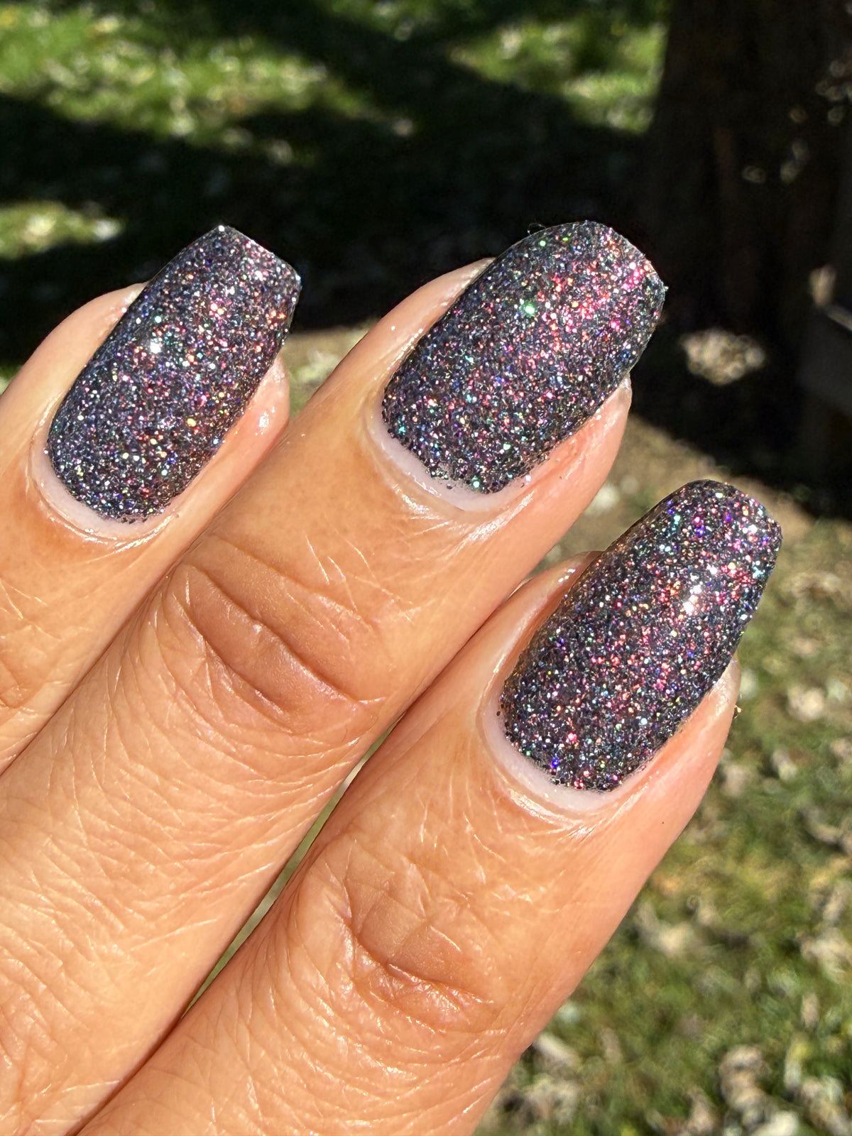 red sparkles with lavender reflective glitter in a dark base over nails outside