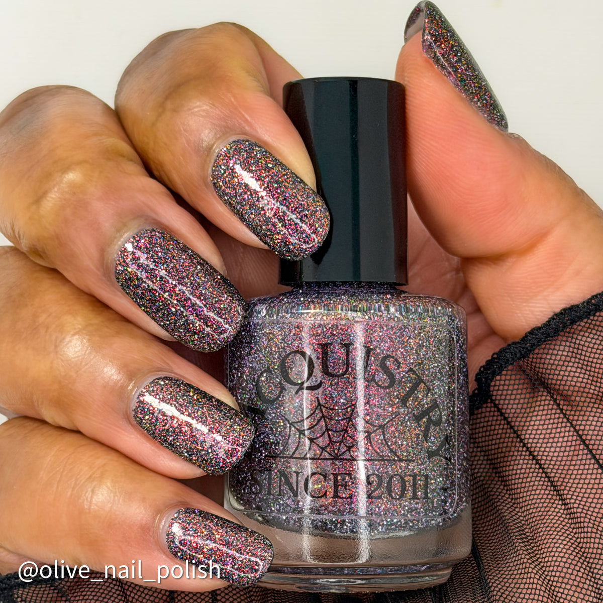 red sparkles with lavender reflective glitter in a dark base over nails holding bottle that says LACQUISTRY SINCE 2011