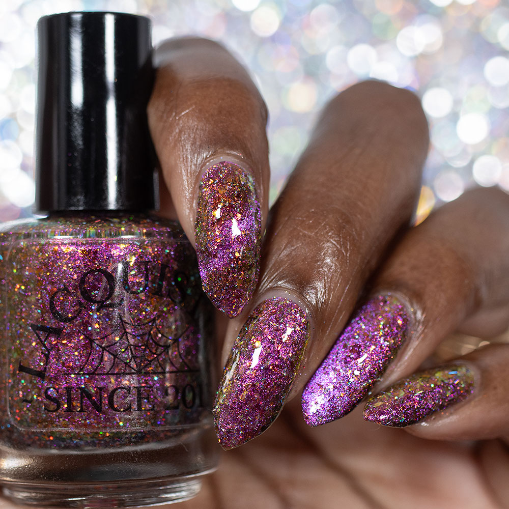 flakie magnetic polish showing red, orange, gold, green flakes, holo glitter, and magnetic effect of fuchsia to purple holding Lacquistry bottle