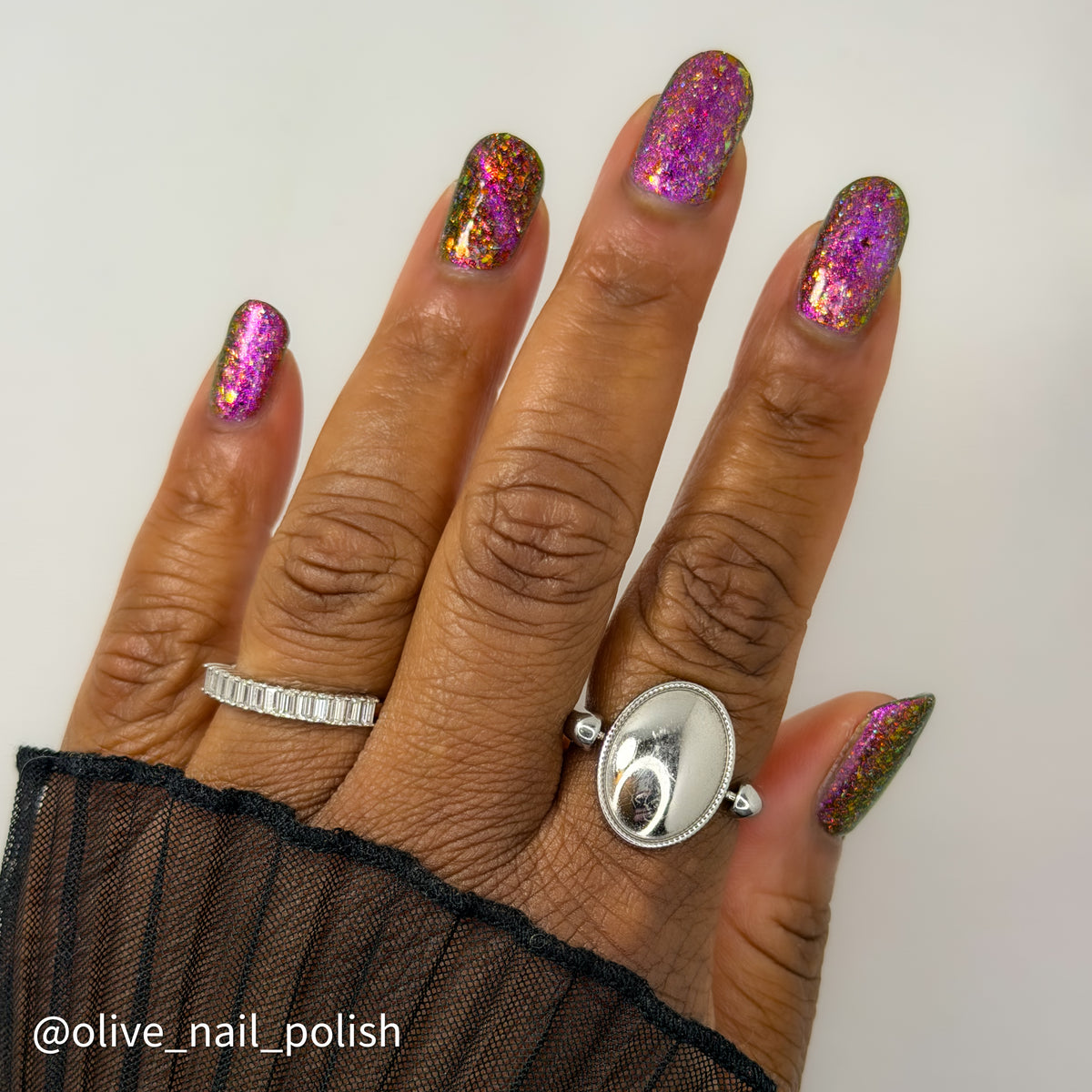 flakie magnetic polish showing red, orange, gold, green flakes, holo glitter, and magnetic effect of fuchsia to purple