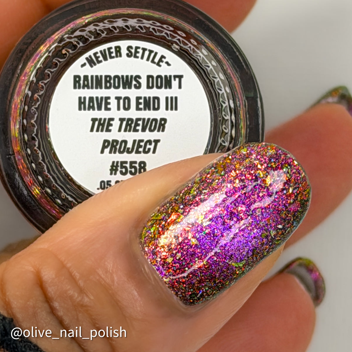 flakie magnetic polish showing red, orange, gold, green flakes, holo glitter, and magnetic effect of fuchsia to purple with rainbows don't have to end III the Trevor Project