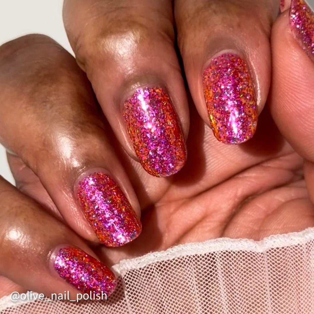 short nails on dark skin tone wearing bright pink sparkling flake and glitter nail polish