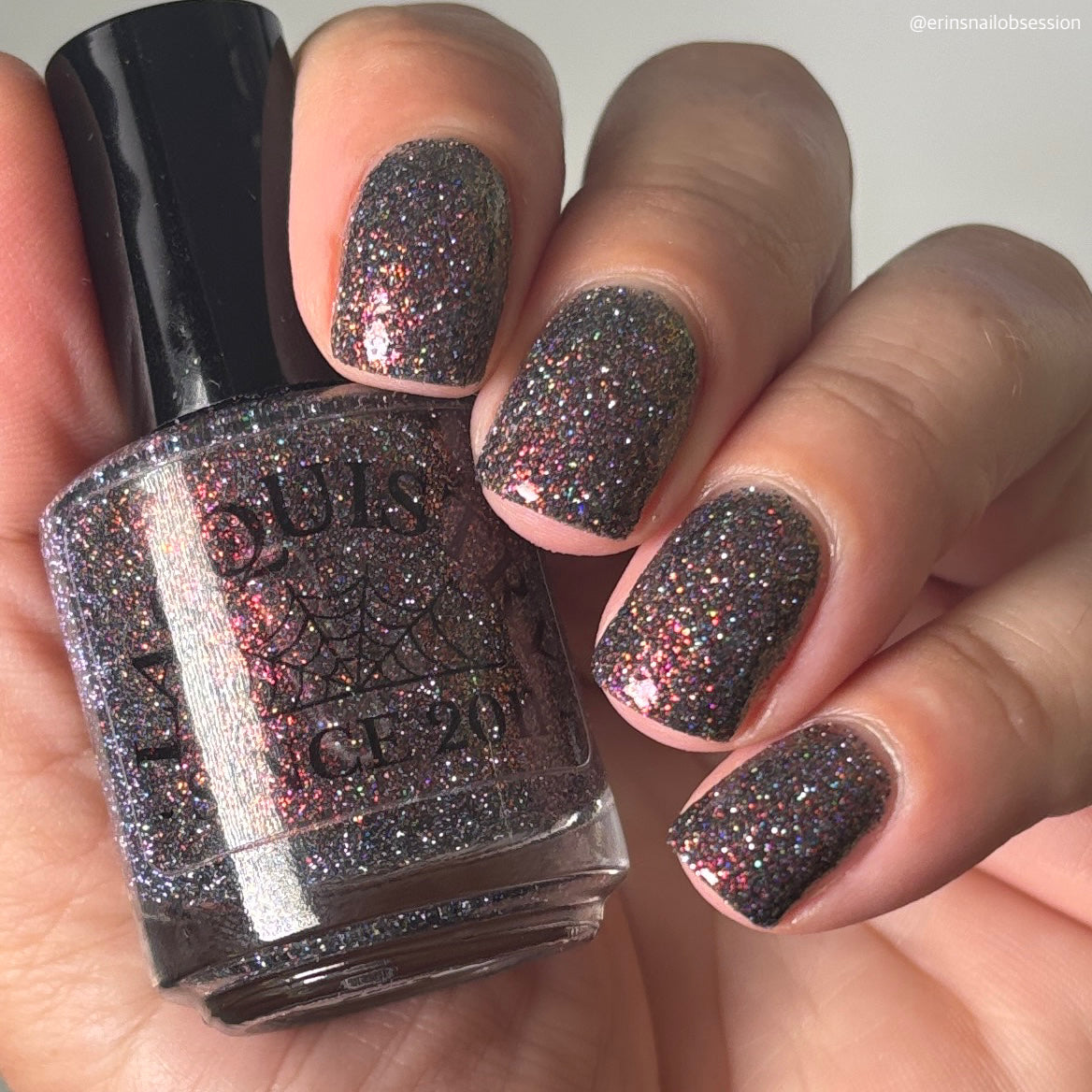 red sparkles with lavender reflective glitter in a dark base over nails holding bottle that says LACQUISTRY SINCE 2011