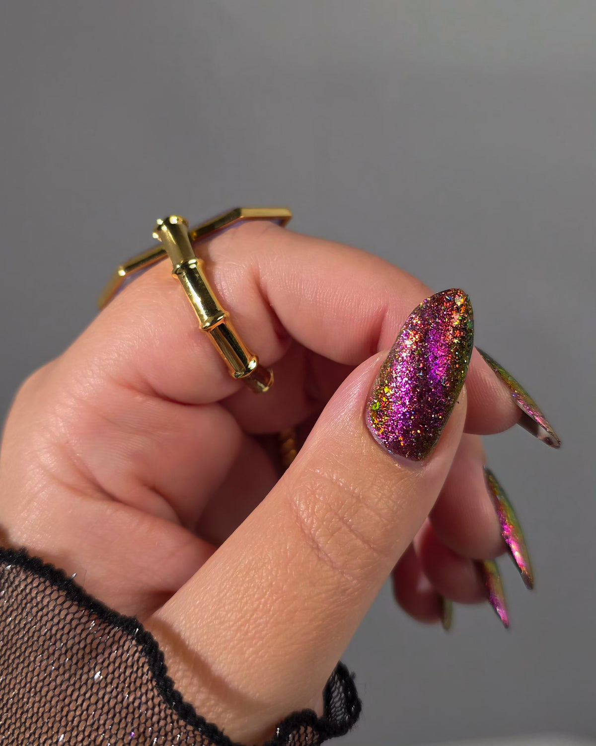 flakie magnetic polish showing red, orange, gold, green flakes, holo glitter, and magnetic effect of fuchsia to purple