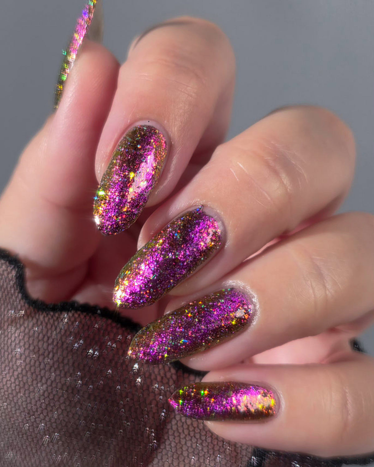 flakie magnetic polish showing red, orange, gold, green flakes, holo glitter, and magnetic effect of fuchsia to purple