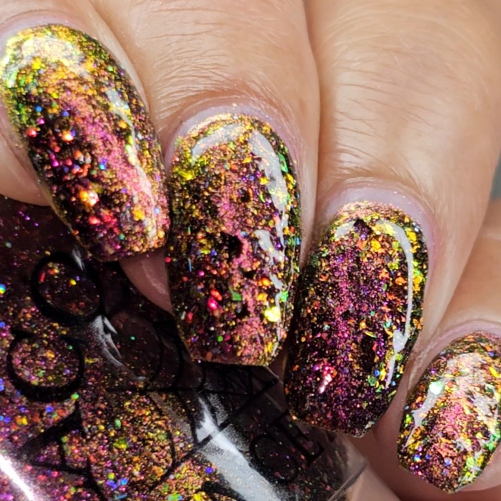 flakie magnetic polish showing red, orange, gold, green flakes, holo glitter, and magnetic effect of fuchsia to purple