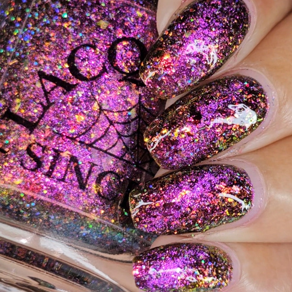 flakie magnetic polish showing red, orange, gold, green flakes, holo glitter, and magnetic effect of fuchsia to purple