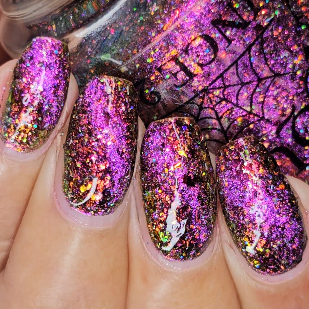 macro shot of flakie magnetic polish showing red, orange, gold, green flakes, holo glitter, and magnetic effect of fuchsia to purple