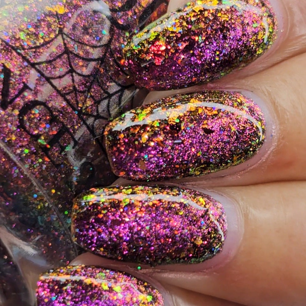 flakie magnetic polish showing red, orange, gold, green flakes, holo glitter, and magnetic effect of fuchsia to purple