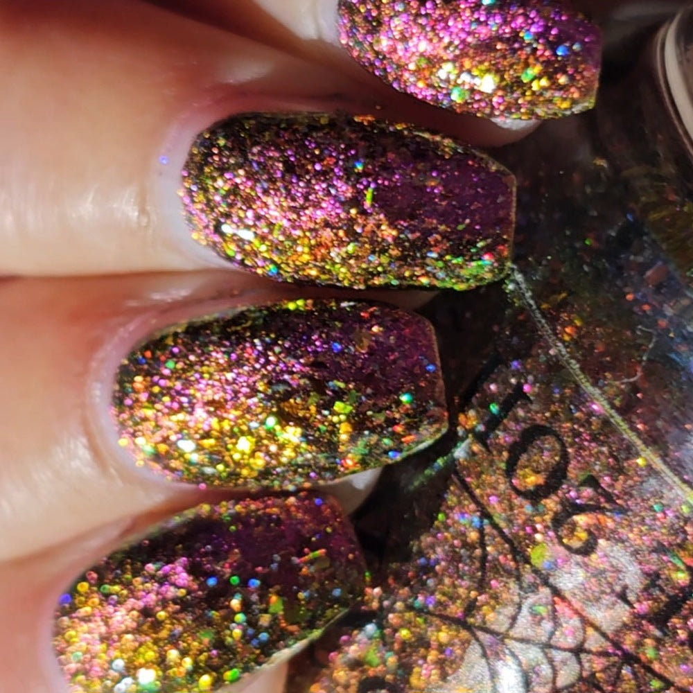 flakie magnetic polish showing red, orange, gold, green flakes, holo glitter, and magnetic effect of fuchsia to purple