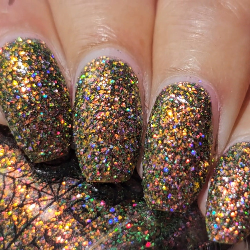 nails painted with sparkly glittery polish showing pink, red, green, gold and orange glitters in a darkened base color with green reflective glitter