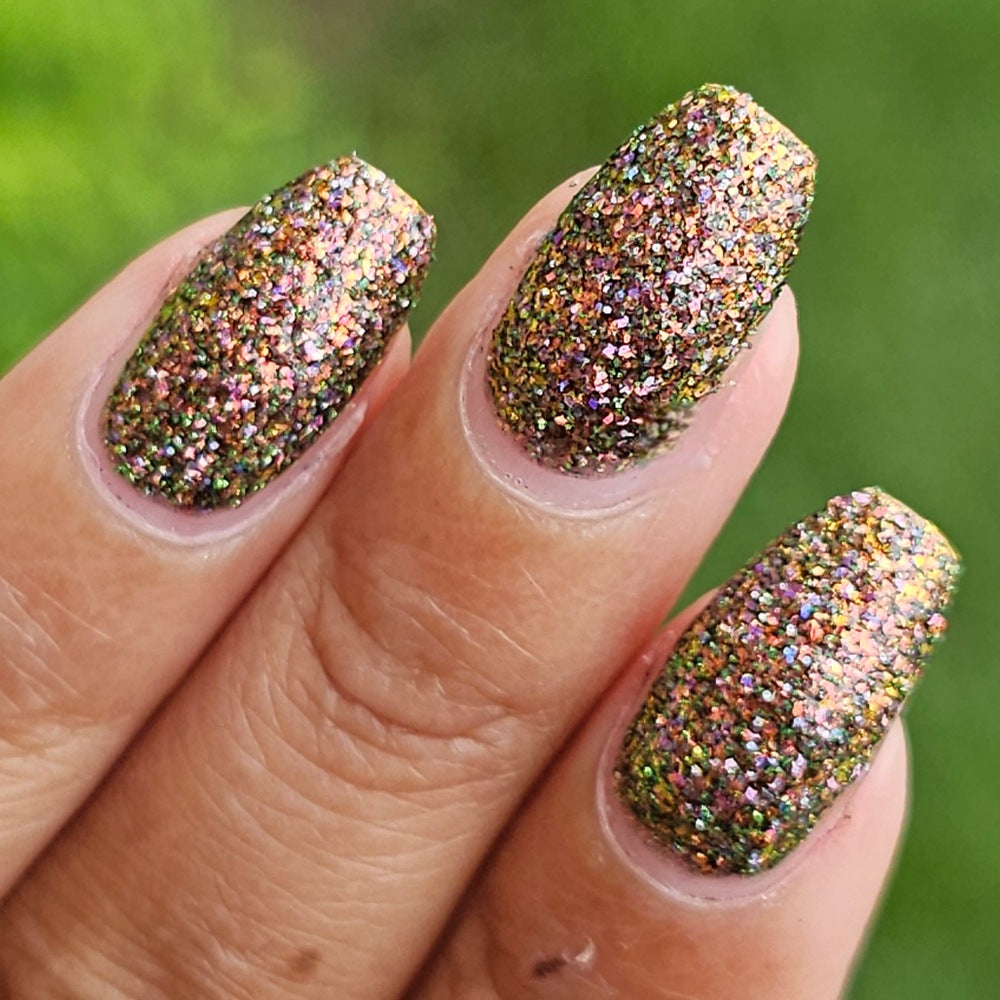 nails painted with sparkly glittery polish showing pink, red, green, gold and orange glitters in a darkened base color with green reflective glitter