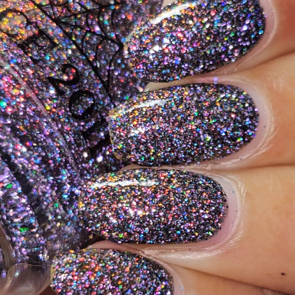 red sparkles with lavender reflective glitter in a dark base over nails holding bottle 