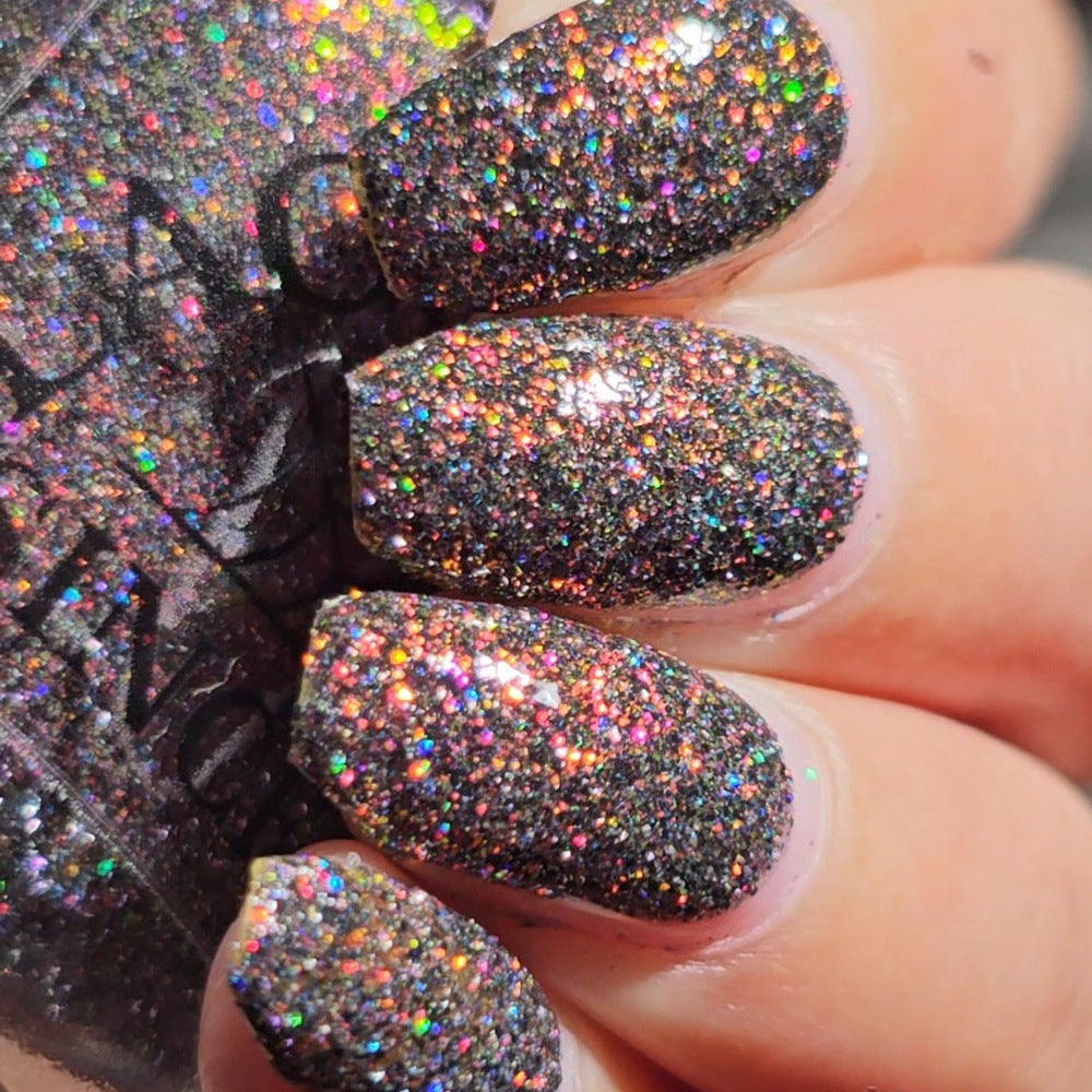 red sparkles with lavender reflective glitter in a dark base over nails holding bottle that says LACQUISTRY SINCE 2011
