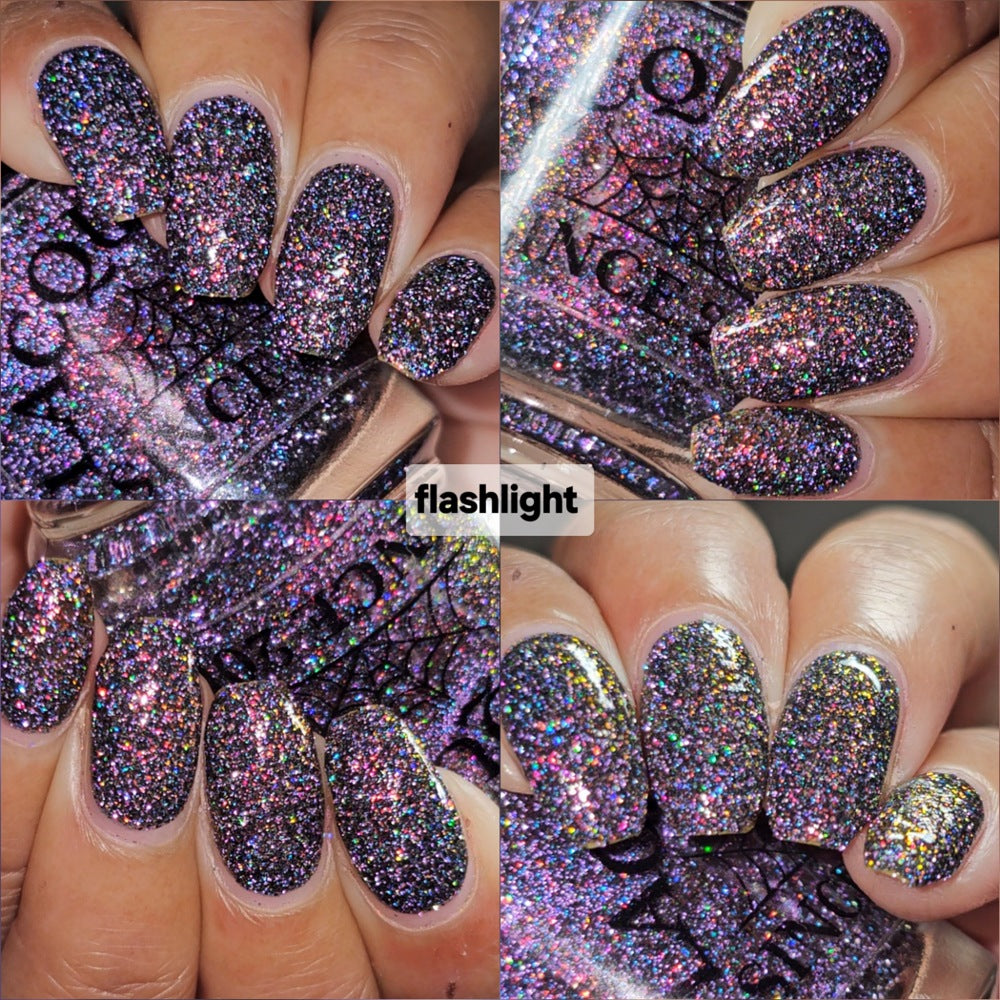 red sparkles with lavender reflective glitter in a dark base over nails holding bottle that says LACQUISTRY SINCE 2011 with flash on