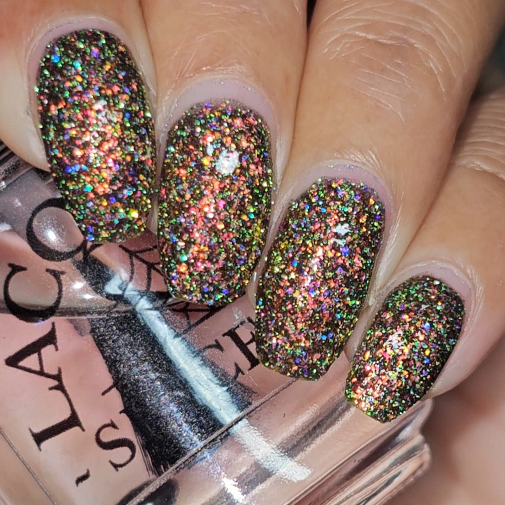 macro of shiny glittery nails holding clear topcoat bottle