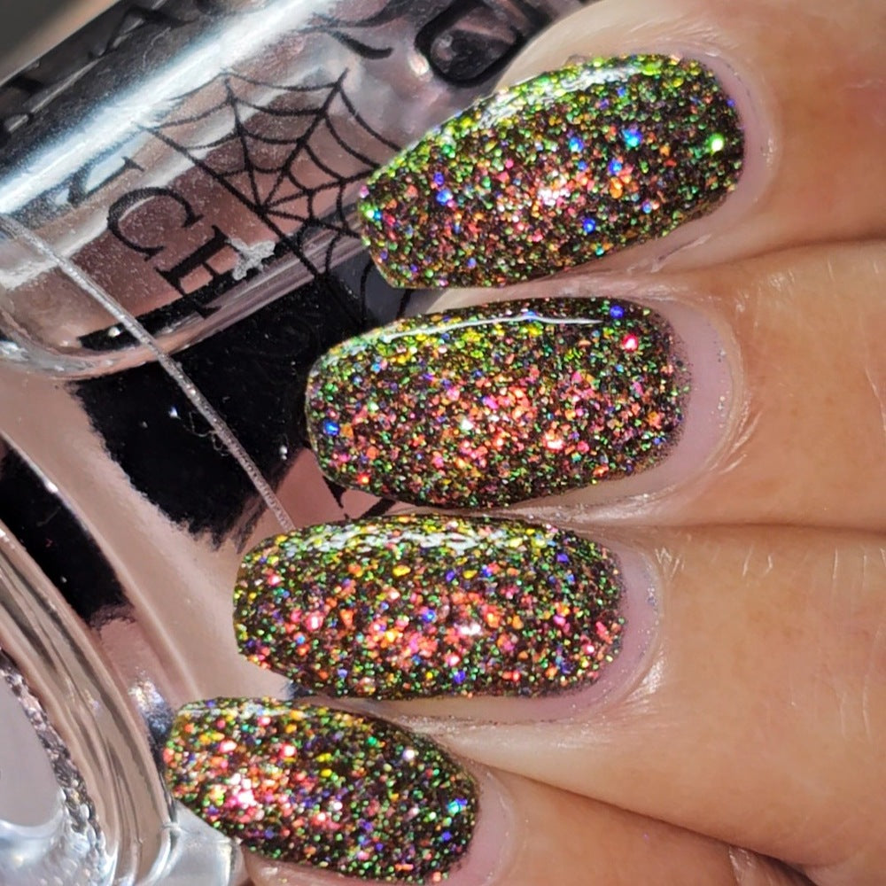 macro of shiny glittery nails holding clear topcoat bottle