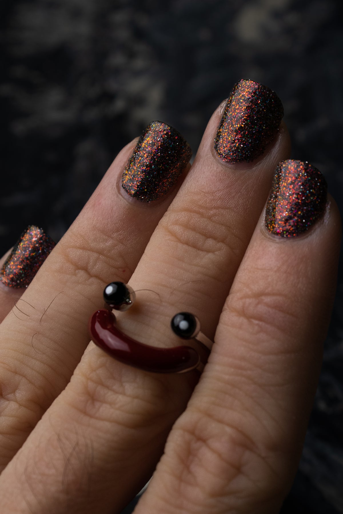 red sparkles with reflective glitter in a dark base over nails