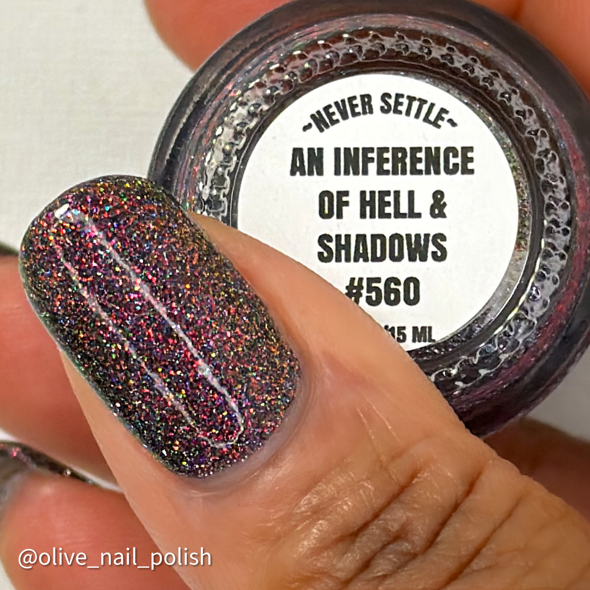red sparkles with lavender reflective glitter in a dark base over nails holding bottle that says an inference of hell & shadows