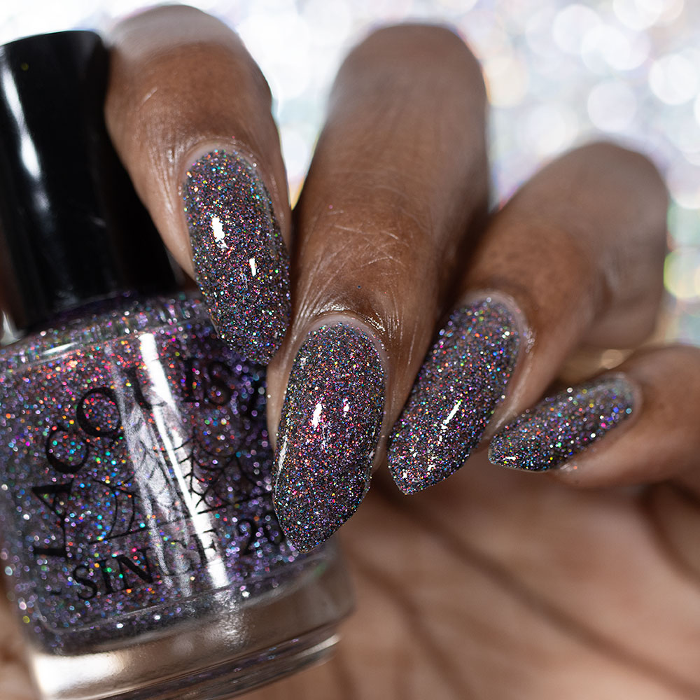 red sparkles with lavender reflective glitter in a dark base over nails holding bottle that says LACQUISTRY SINCE 2011