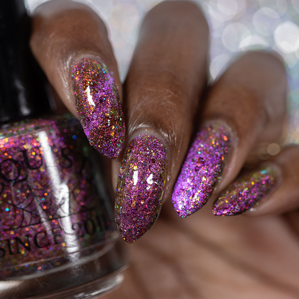 flakie magnetic polish showing red, orange, gold, green flakes, holo glitter, and magnetic effect of fuchsia to purple