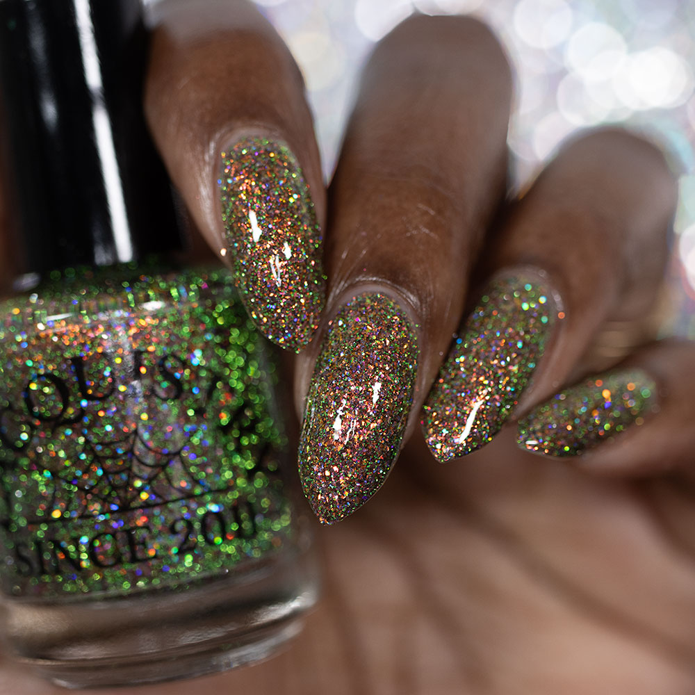 nails painted with sparkly glittery polish showing pink, red, green, gold and orange glitters in a darkened base color holding bottle of polish