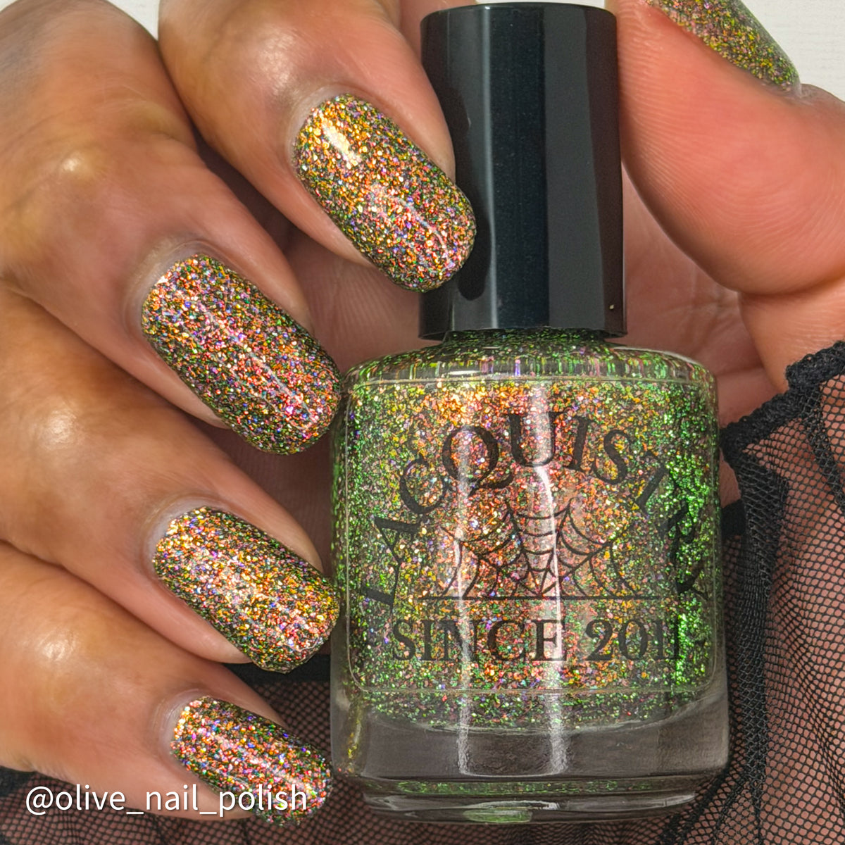 nails painted with sparkly glittery polish showing pink, red, green, gold and orange glitters in a darkened base color with green reflective glitter