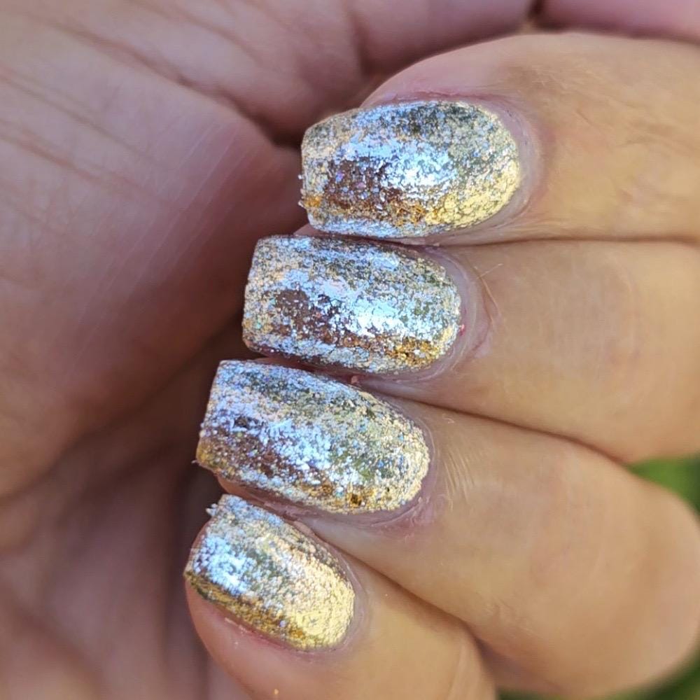 A close-up of a hand showing manicured fingernails painted with a textured, glittery silver