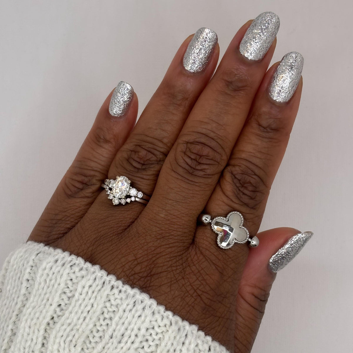 A close-up of a hand with nails painted in a shiny silver glitter nail polish,