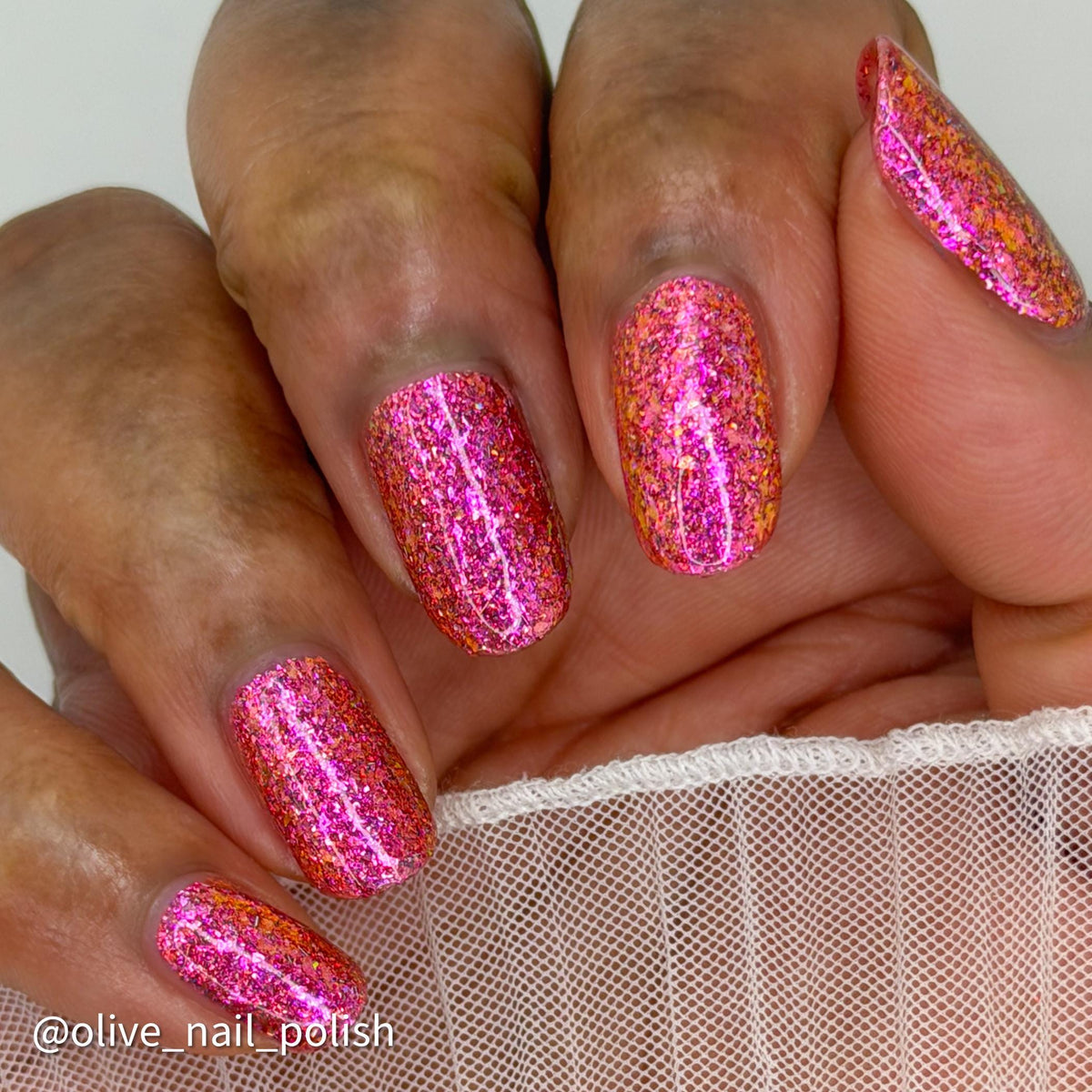short nails on dark skin tone wearing bright pink sparkling flake and glitter nail polish 