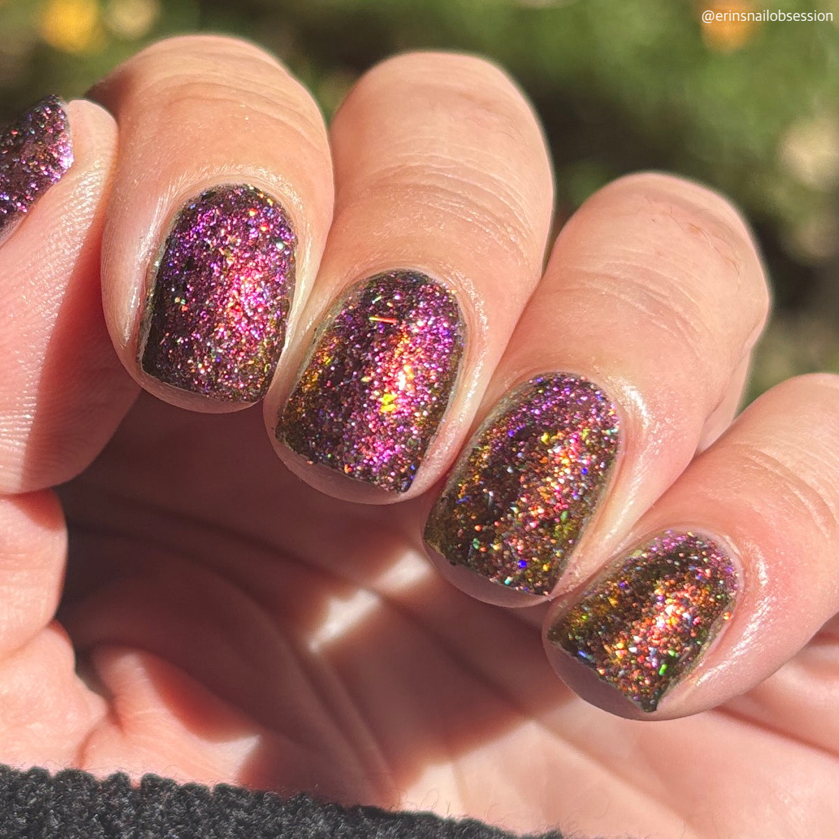 flakie magnetic polish showing red, orange, gold, green flakes, holo glitter, and magnetic effect of fuchsia to purple in the sun