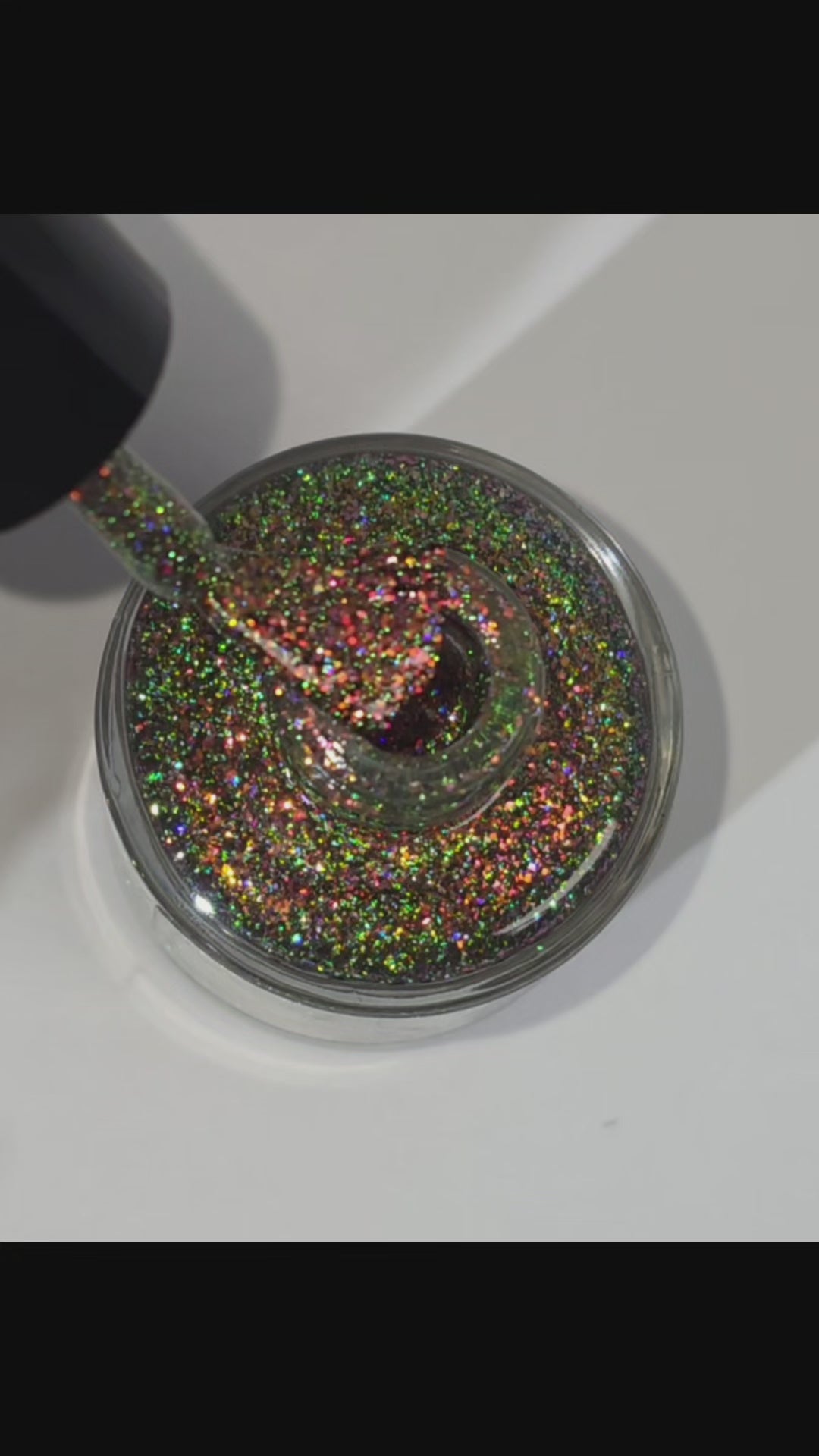 sparkly glittery polish showing pink, red, green, gold and orange glitters in a darkened base color with green reflective glitter