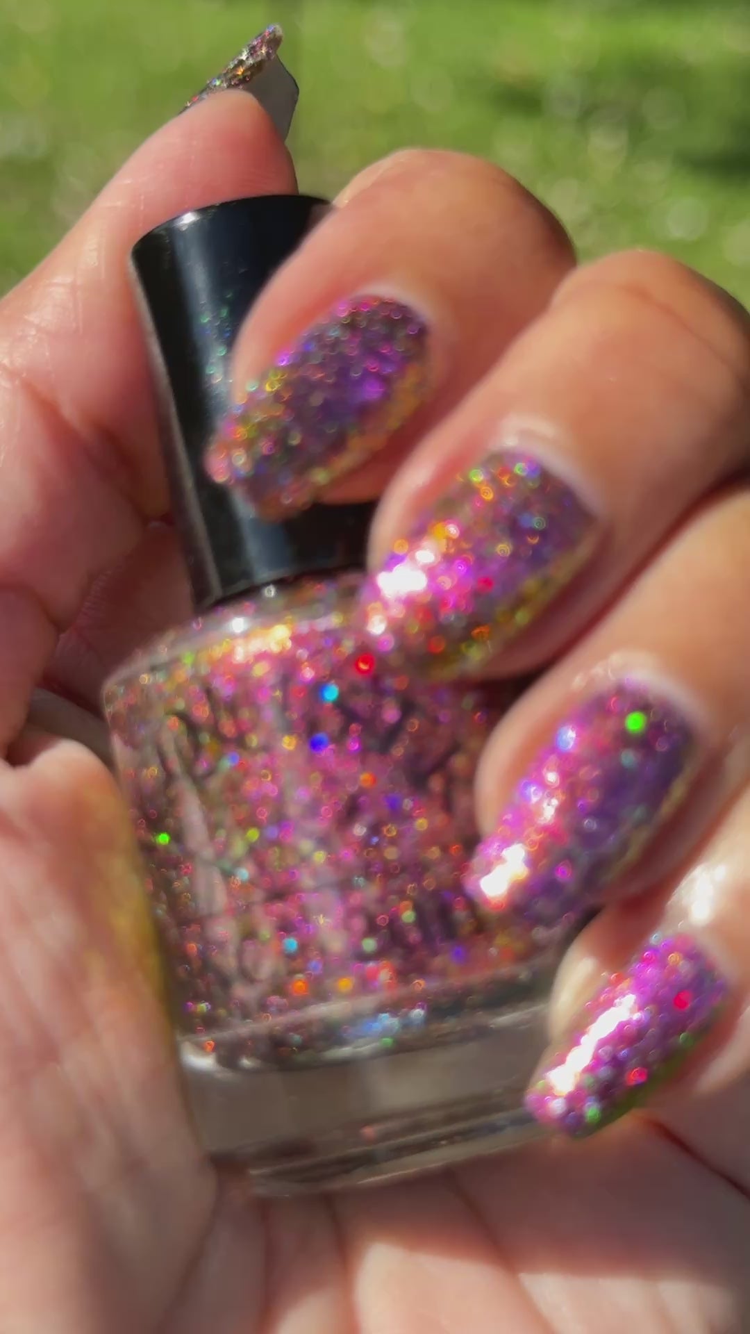 video in the sun of flakie magnetic polish showing red, orange, gold, green flakes, holo glitter, and magnetic effect of fuchsia to purple